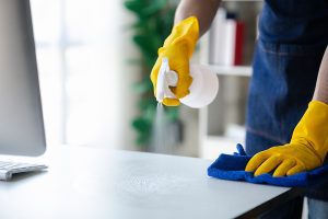 close up photo of a professional cleaner disinfecting a desk